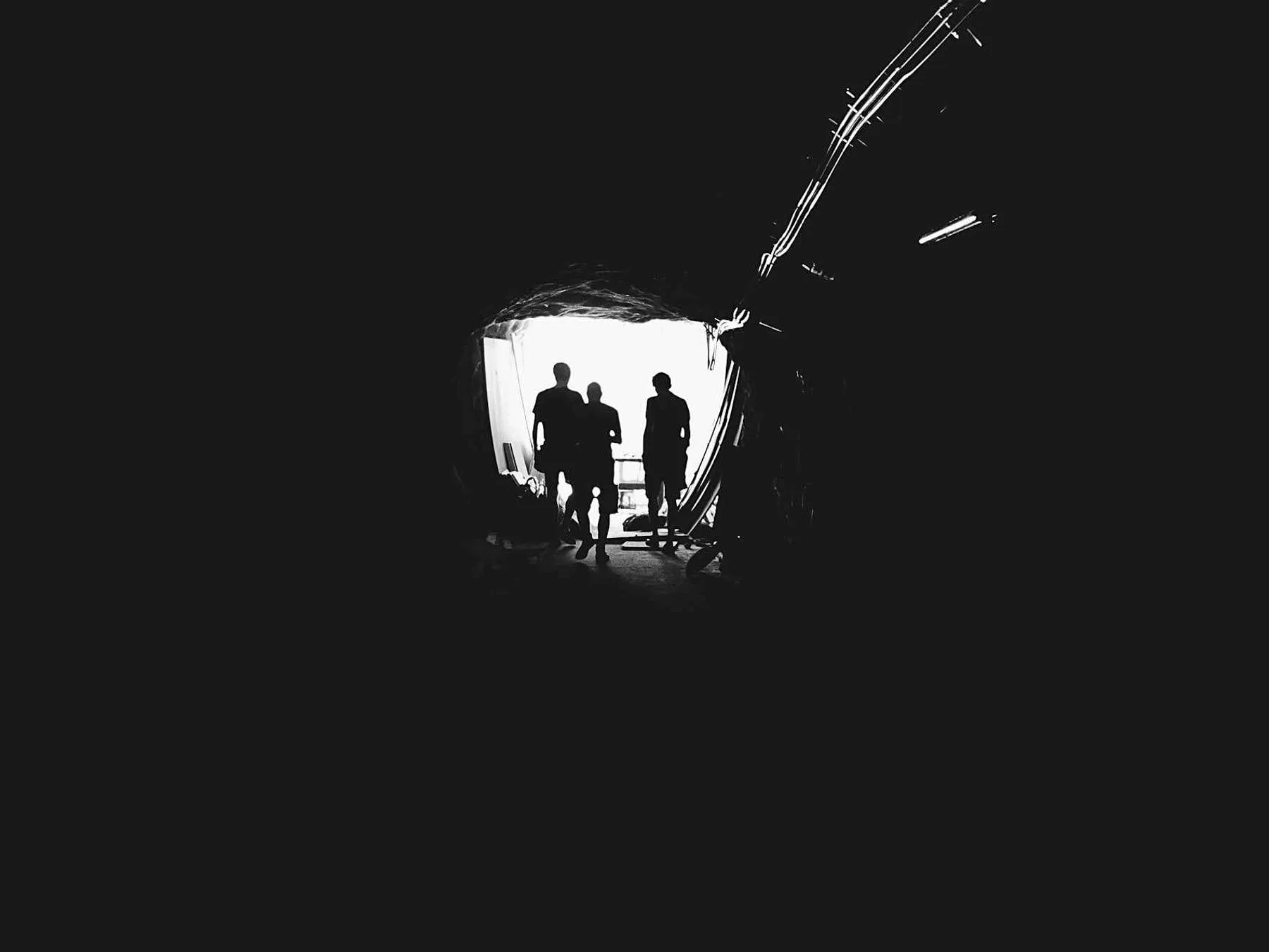 Two figures at the bright mouth of a dark tunnel