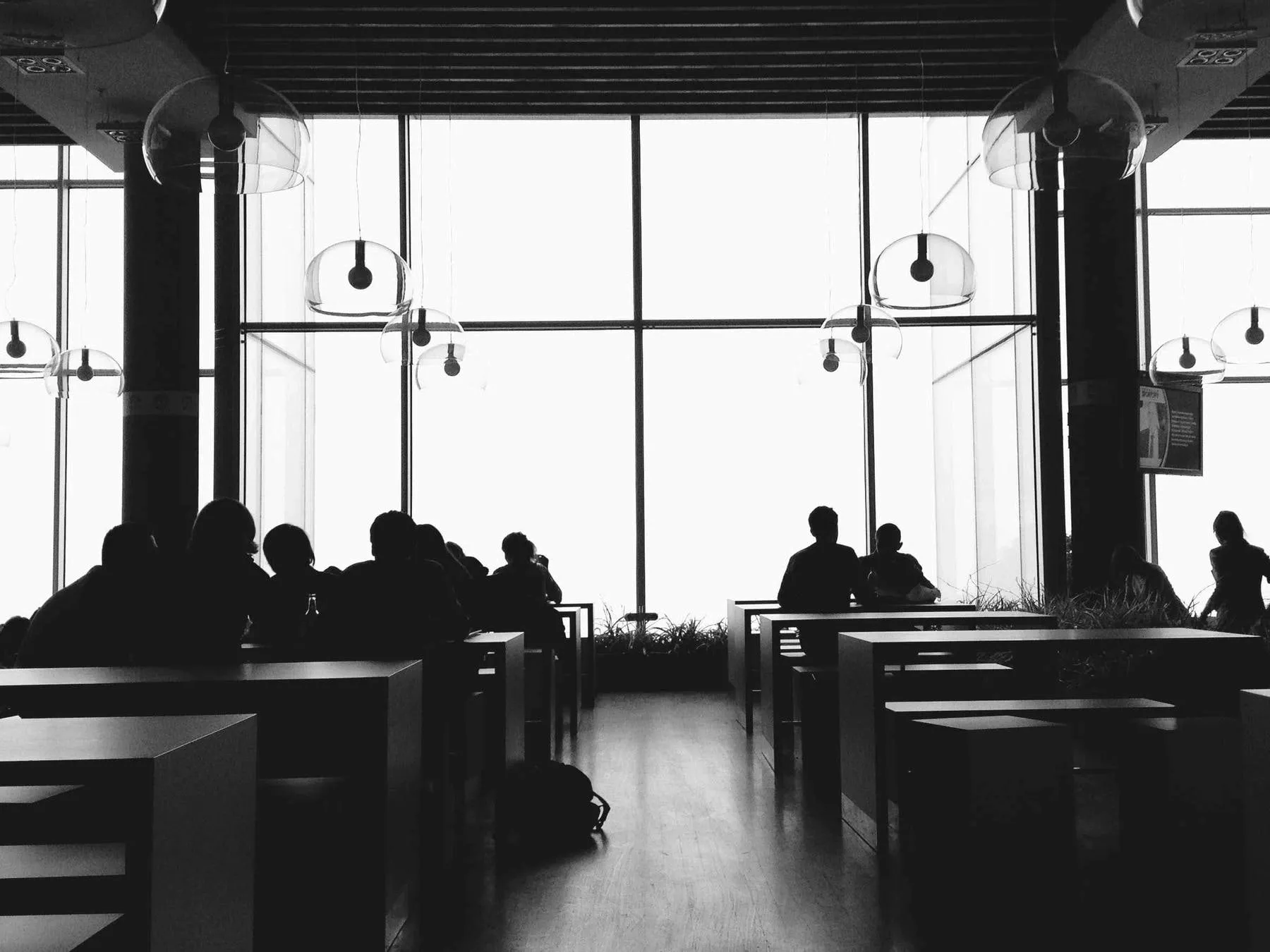 Silhouettes of guests at a long window table in a hotel lounge